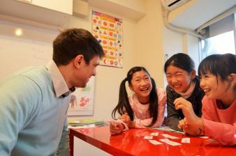 外国人講師から3人の女の子が英語のグループレッスンを受けている